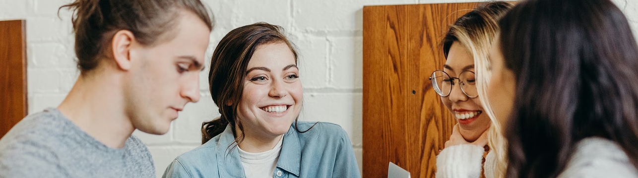 A young man and three young women chatting in a circle.