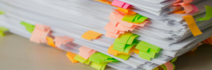 A stack of papers organized with multicolored sticky note markers along the sides